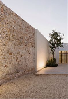 an exterior view of a modern house with stone walls and trees in the foreground