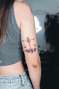 a woman with a cross tattoo on her left arm and the other arm behind her