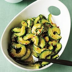 a white bowl filled with sliced zucchini on top of a green tablecloth