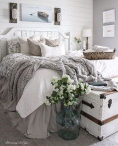 a white bed sitting in a bedroom next to a vase with flowers on top of it