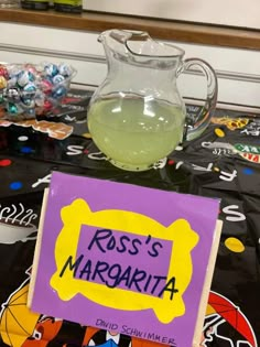 a glass pitcher filled with liquid next to a sign that says ross's margarita