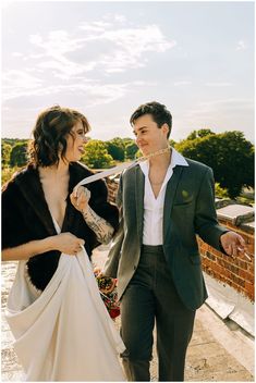 a man in a suit and tie walking next to a woman wearing a wedding dress