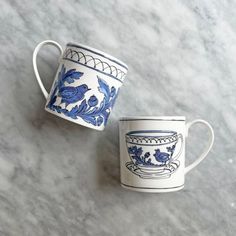 two blue and white cups sitting on top of a marble counter