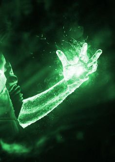 a person holding out their hand with green light shining on it in the dark,