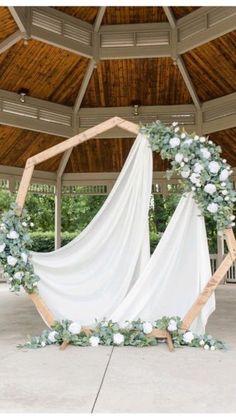 a wedding arch decorated with white flowers and greenery