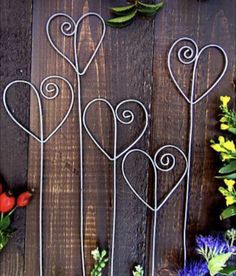 four metal hearts on a wooden table with flowers