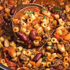 a ladle full of chili macaroni and cheese soup being stirred with a spoon