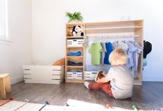 a child sitting on the floor in front of a closet