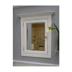 a bathroom mirror with a white frame and flower in the vase on the wall next to it