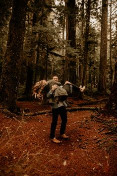 a man is walking through the woods with his back to the camera and holding onto another person's shoulders