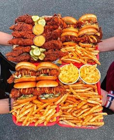 a table topped with lots of hot dogs covered in toppings next to french fries and macaroni and cheese