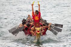 a group of people riding on top of a boat in the water with paddles