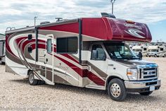 an rv parked on gravel with other vehicles in the background