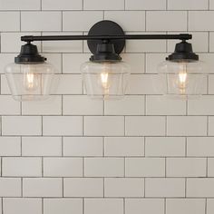 three light fixtures mounted on a white brick wall