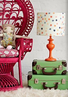 two pieces of luggage sitting next to a pink chair and lamp on a white rug