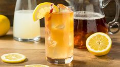 a pitcher of lemonade next to two glasses of lemonade on a wooden table