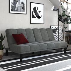 a gray couch sitting on top of a black and white striped floor next to a potted plant