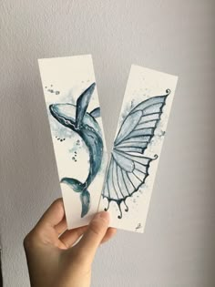 someone holding up two cards with watercolors on them, one is blue and the other is white