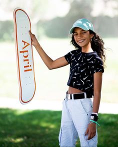 a woman holding up a skateboard in front of her face and smiling at the camera