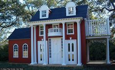 a red and white house with two balconies on the top floor, surrounded by trees