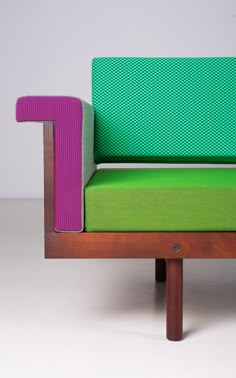 a green and purple couch sitting on top of a wooden frame