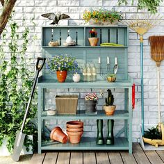 an outdoor garden with potted plants and gardening tools on shelves next to a brick wall