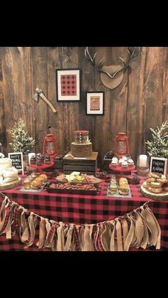 a table topped with lots of food next to a wooden wall and deer antlers on the wall