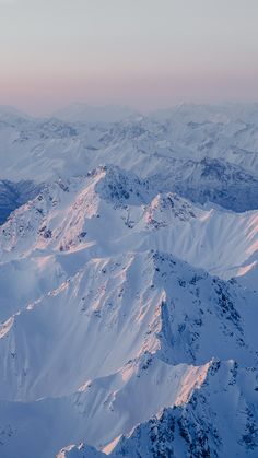 the mountains are covered in snow at sunrise or sunset, as seen from an airplane