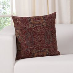 a white couch with a red pillow on top of it next to a windowsill