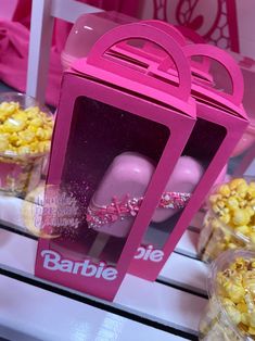 there is a pink box that has popcorn in it and some other boxes behind it