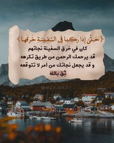 an image of a sign in arabic on the side of a lake with houses and mountains in the background