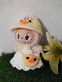 a crocheted doll holding a stuffed animal in its arms and sitting next to a daffodil flower