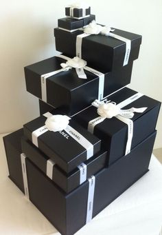 three black boxes with white ribbons are stacked on top of each other and one has a bow