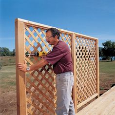 a man using a drill to attach a trellis on a wooden deck in front of a house