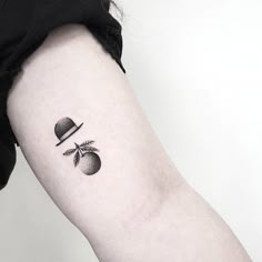 a black and white photo of an apple with a top hat tattoo on the arm