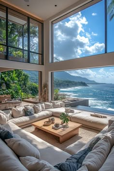 a living room filled with lots of furniture and large windows overlooking the ocean in front of it