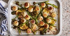 a white dish filled with scallops and asparagus on top of a table