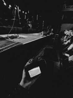 a black and white photo of a person holding a camera in front of a stage