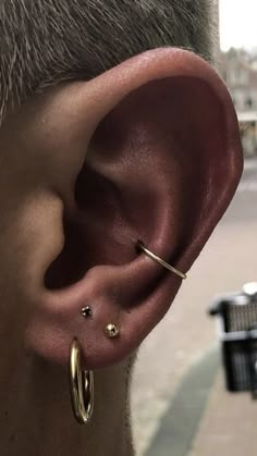 a close up of a persons ear with two small gold hoops on the side