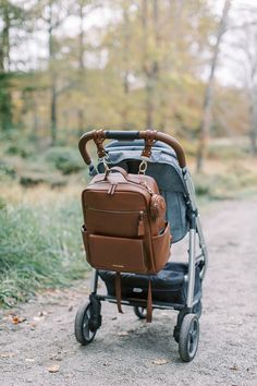 a baby stroller with a backpack strapped to the handlebars on it's wheels