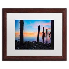 an image of a beautiful sunset over the water with old wooden posts in the foreground