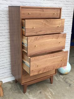 a wooden dresser sitting in front of a brick wall with drawers on each side and one drawer open