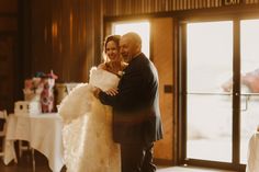 a bride and groom hugging each other in front of a large window at their wedding reception