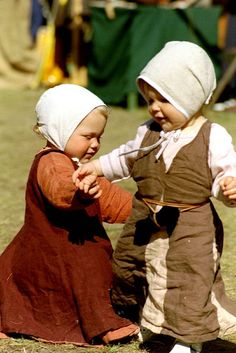 two small children playing with each other in the grass