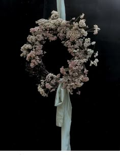 a white bow tied around a wreath with pink flowers