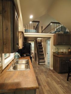 a kitchen with wooden floors and stairs leading up to the second floor in a home