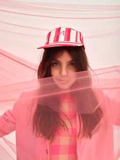 a woman wearing a red hat and pink jacket with her hands on her hips, posing for the camera