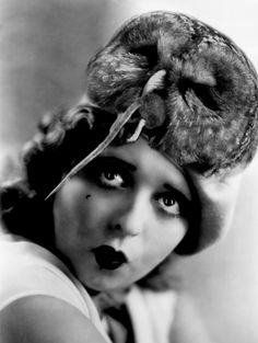 an old photo of a woman wearing a hat with a bird on it's head