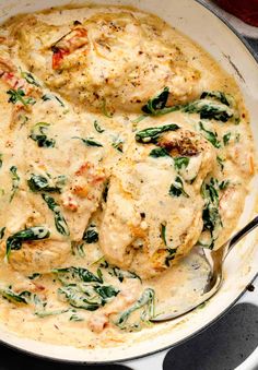 a pan filled with chicken and spinach covered in sauce