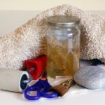 a jar with scissors and other items sitting on a table next to a pile of towels